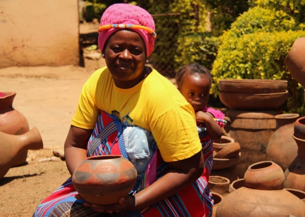 Florah Randela with baby on her back - showing off one of her beautiful pots