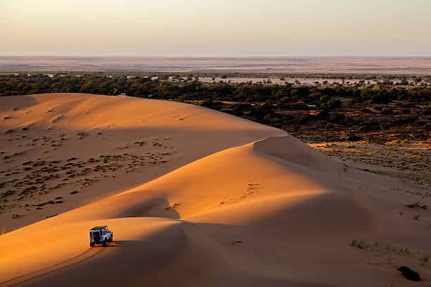 A car is driving through sand dunes