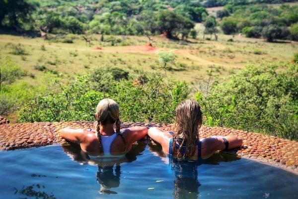 Two women in a plunge pool looking out over the edge at valley below - Soutpansberg South Africa