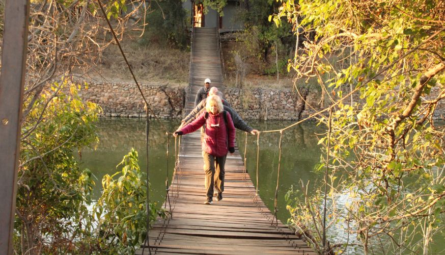Woman walking towards the camera over the suspension bridge to our Limpopo Island Camp