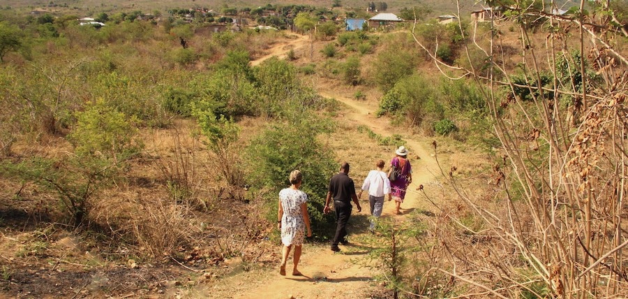 Alexandra's Africa guests walking on dusty path to African Village