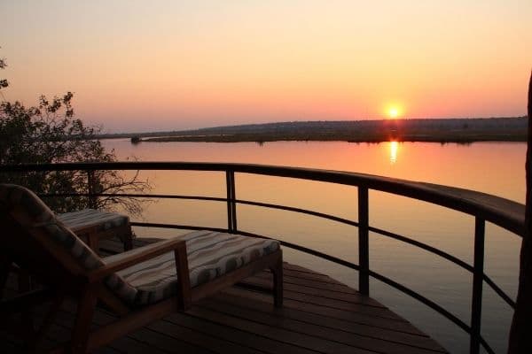 Looking out over the Chobe River from the balcony of one of our Tailored Safari Hotels with the sun setting in the background