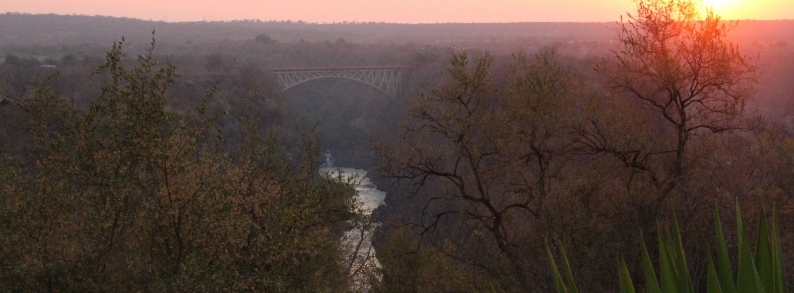 Victoria Falls Bridge over the Zambezi River at Sunset Photo at Sunset of the Victoria Falls Bridge from a distance with Zambezi river flowing below